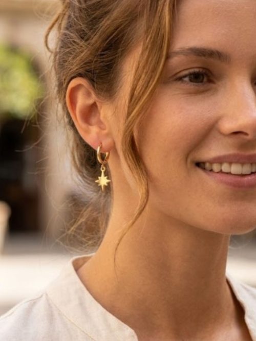 Créoles dorées étoile du Nord en acier inoxydable portées par une jeune femme